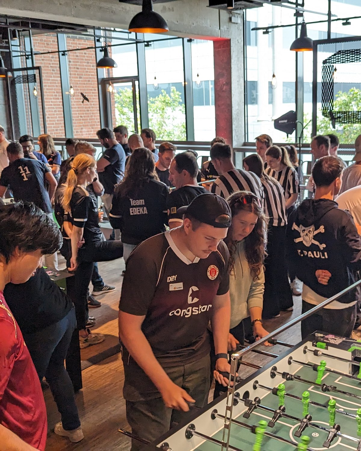 Kolleg:innen spielen bei einer Firmenfeier gemeinsam Tischfußball