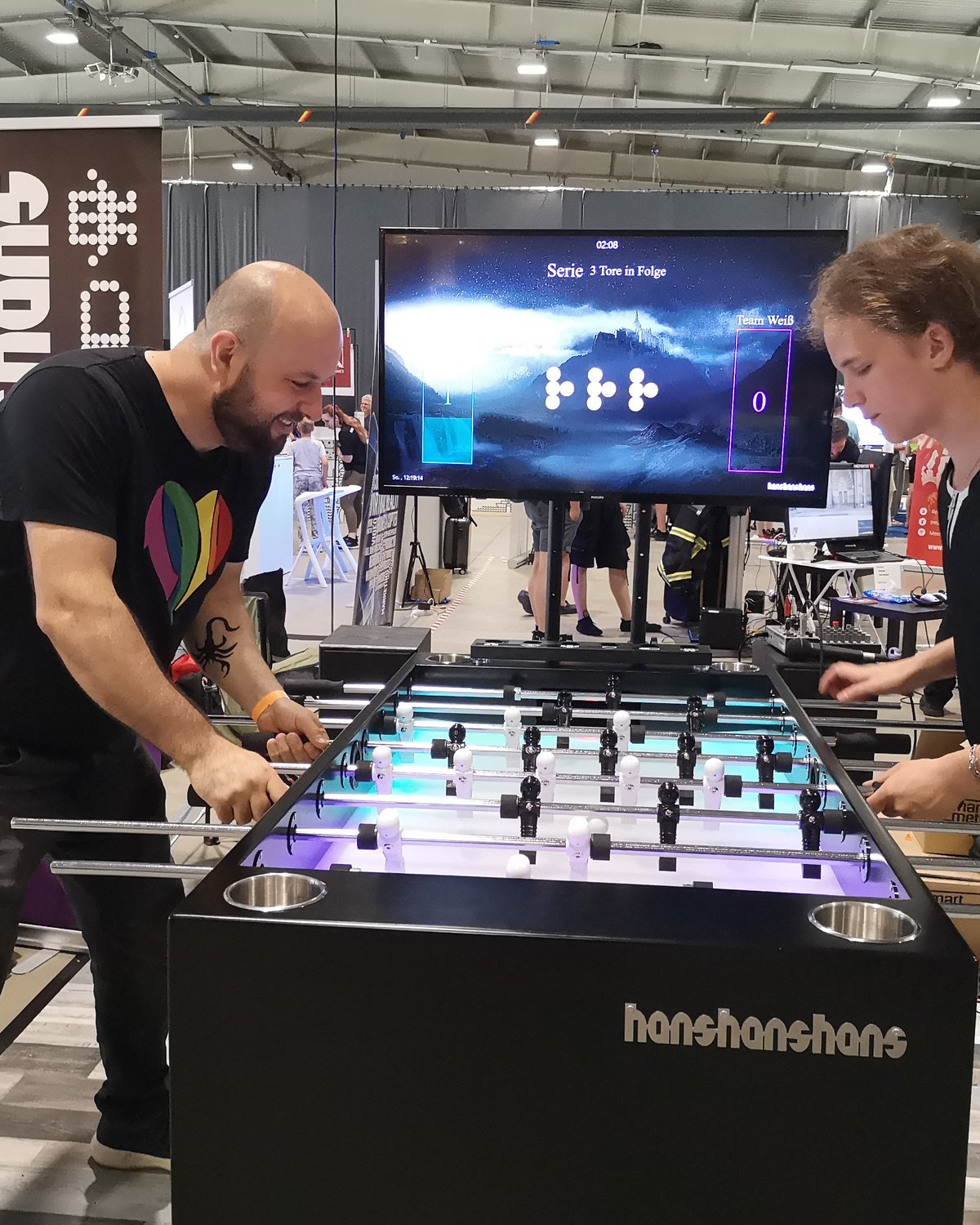 Besucher:innen spielen an einem Kickertisch auf einem Messestand